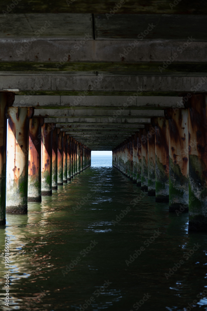 Fototapeta premium View under a pier with repeating supports over seawater