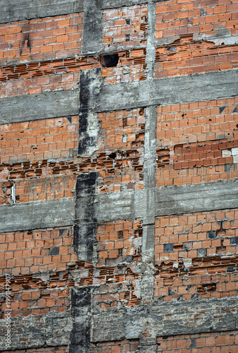 An unplastered, dilapidated wall. The bricks and concrete are visible. Damaged brick wall. urban transformation,