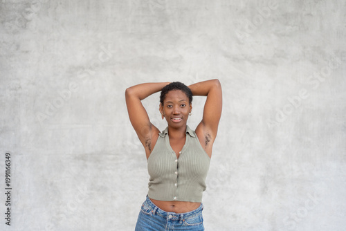 Tableau sur toile Young woman standing with arms raised showing underarm hair, smiling at camera a