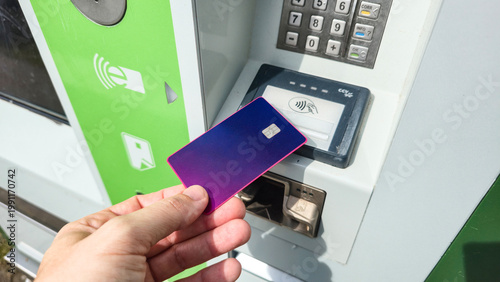  Hand holding purple credit card near contactless payment terminal, finance.