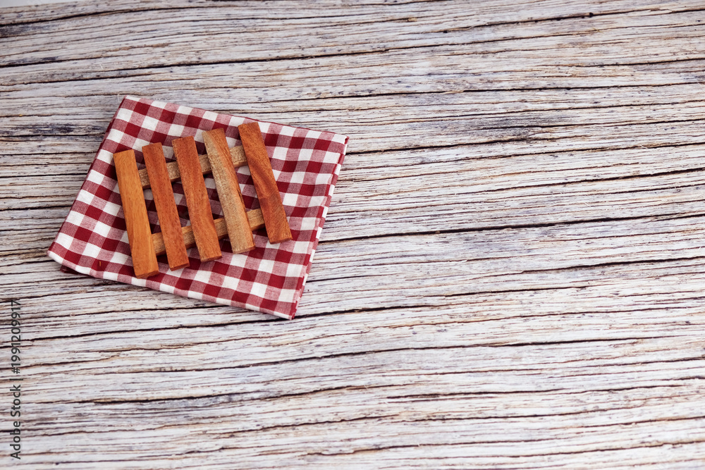 Fototapeta premium Mini Wooden pallets on checkered cloth. Rustic table beneath provides textured backdrop. Warm tones suggest cozy, vintage charm. Perfect for kitchen, bathroom, or home decor scenes