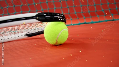 Racket lifting and revealing yellow tennis ball rolling toward green net with gold stars for sports