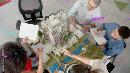 Designer pointing at model, team tapping tablet, noting, reviewing design with overlays over model