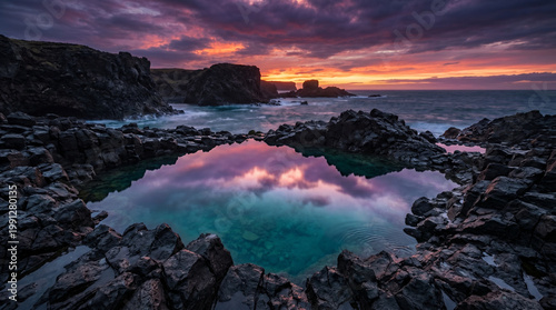 Dramatic sunset reflecting in a rocky tidal pool on rugged coast