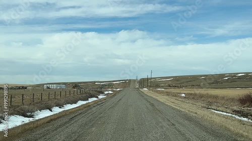 Wide angle POV driving across flat prairie terrain on unpaved road under expansive Alberta sky