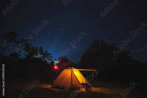 nature traveling with orange camping tent on mountain with milky way and star background
