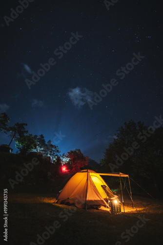 nature traveling with orange camping tent on mountain with milky way and star background
