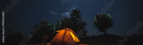 nature traveling with orange camping tent on mountain with milky way and star background