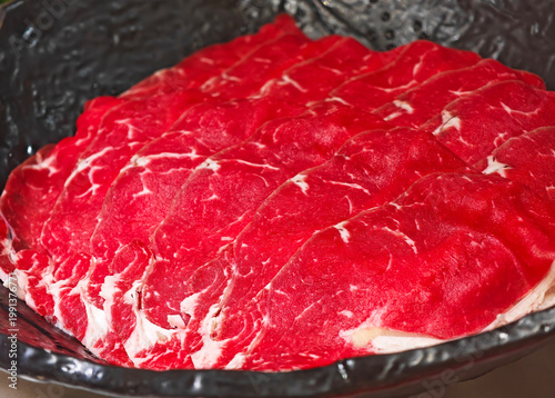 Close-up fresh raw beef slices in a black plate.