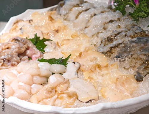 Close-up fresh seafood platter with assorted raw shellfish, scallops, and sea cucumbers on crushed ice on plate
