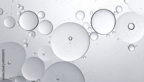 Clean abstract macro background of transparent oil bubbles in white and silver tones.