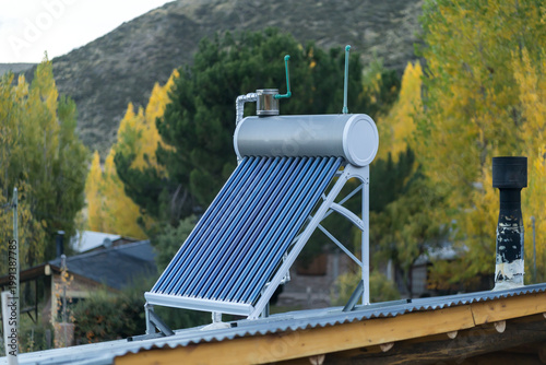 Solar water heater system installed on a rooftop with autumn trees in the background