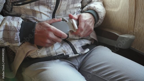 Person fastens and tightens seat belt on airplane closeup. Safety measures during takeoff, landing, and turbulence. Caucasian man hands interacting with aircraft equipment.