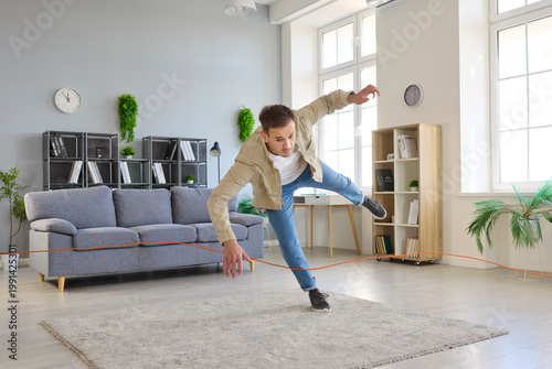 Obraz na plátne Accident of tripping over cord at home, home hazard for man walking to trip and fall on living room floor