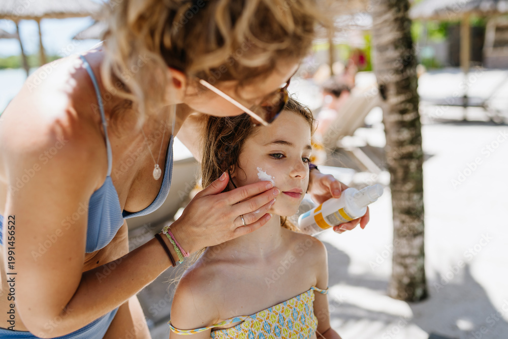 Obraz premium Mother applying sunscreen on daughters face.