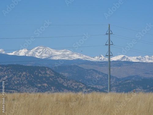 Power Line Pole in Prairie Landscape with Snowy Rocky Mountains, Colorado USA