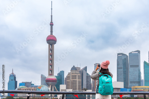 Canvas Print Young woman and a backpack takes a photo of the shanghai skyline, from the bund view point