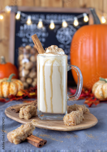 A cozy fall scene featuring a creamy pumpkin spice latte with cinnamon and caramel drizzles.