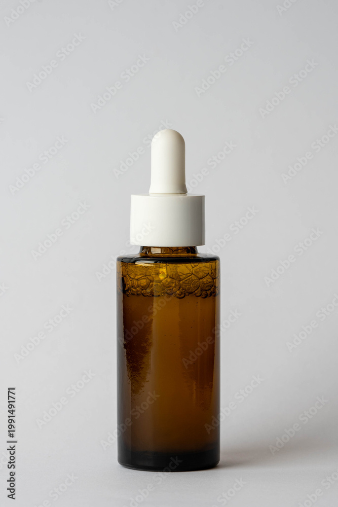 Fototapeta premium Amber glass bottle with dropper on white background, skincare product