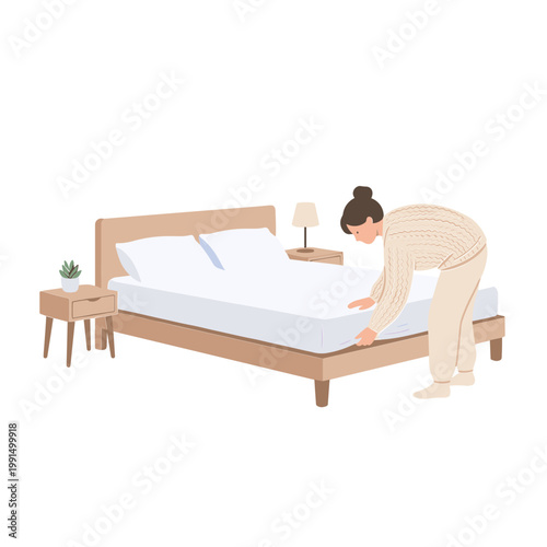 Woman making bed with fitted sheet in bedroom with nightstand and lamp