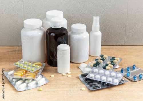Photos Medicine bottles and blister packs with various pills on wood