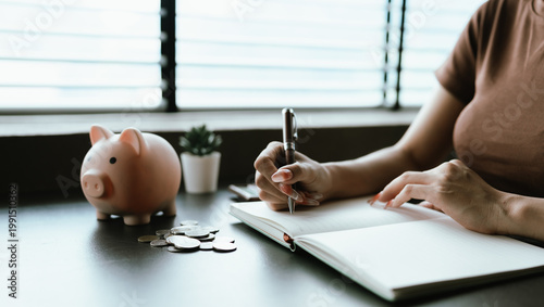 Картината върху платно close-up image shows a woman saving money by dropping coins into a piggy bank while using a calculator, symbolizing budgeting, financial planning, and managing personal savings