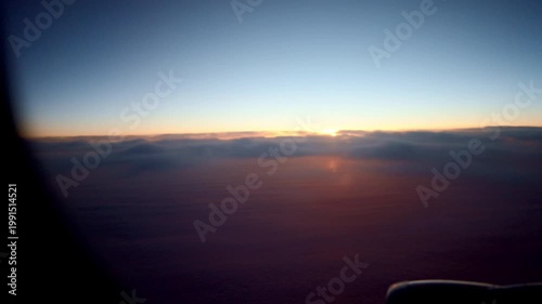 Peaceful Morning Light Casting Over Clouds. Calm Atmosphere With Soft Sunrise Lighting And Distant Sun. Gentle Sunrise Illuminating Tranquil Clouds With Subtle Passenger Silhouette In Background