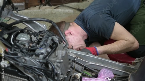 Man Repairing Scooter in a Garage Workshop with Headlamp