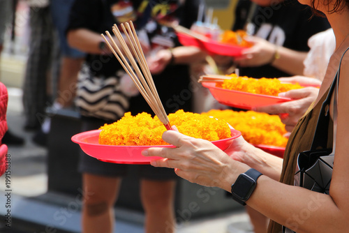Photography A devotee holds a tray of marigolds and incense for prayer