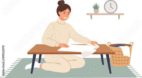 Woman sitting on floor folding laundry in living room with clock