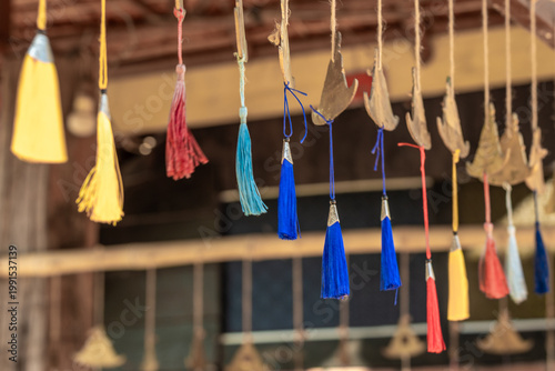 Bilde på lerret A vibrant display of colorful tassels and traditional metallic leaf-shaped ornaments hangs from strings, creating a charming cultural decoration