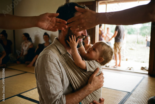 Baby reaching for a fathers beard while resting in a carrier during an indoor family gathering with tender natural light