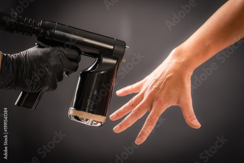 Spraying tanning solution across the hand using a handheld device. Even distribution ensures consistent pigmentation and balanced cosmetic appearance.