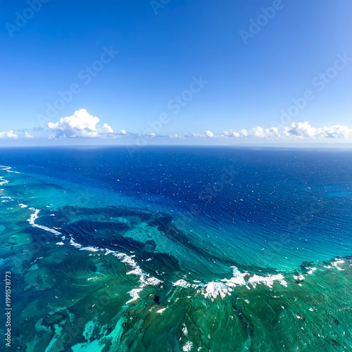 Aerial View Of Vibrant Tropical Coral Reef Showing Turquoise Shallow Water Meeting Deep Blue Ocean Under A Clear Bright With Scattered Clouds