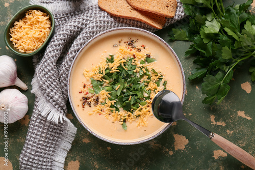 Foto Bowl of tasty cheese soup with parsley and garlic on green background