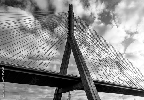 Black and white low-angle view of Flintshire Bridge pylon and stay cables against a dramatic cloudy sky