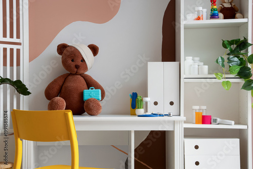 Toy bear with bandage and pill box on pediatrician's desk in office