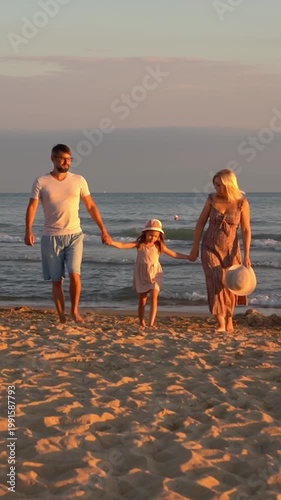 Happy family walks on beach at sea at sunset. Mother father and little daughter on summer vacation. Travel holiday. Vertical shot