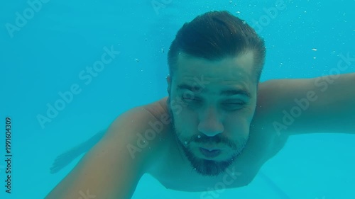 Man swims underwater in pool shoot yourself on action camera. Swimmer dives under water. Summer vacation holiday travel