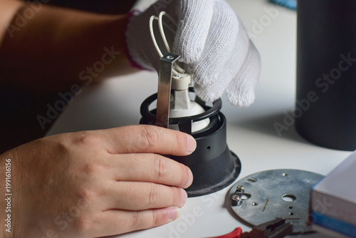 The electrician is removing and reassembling the light bulb.