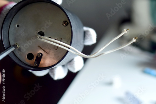 The electrician is removing and reassembling the light bulb.