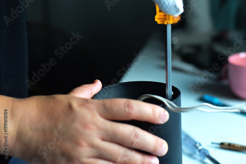 The electrician is removing and reassembling the light bulb.