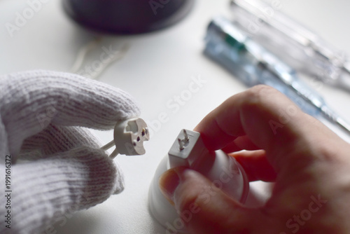 The electrician is connecting the wiring to the light bulb.