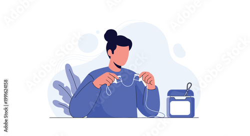 A person wearing a blue sweater carefully prepares a long piece of dental floss for use while a blue floss container sits on a table in the foreground.