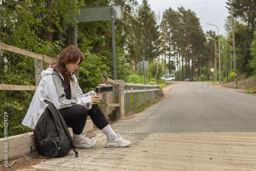 concept of traveling alone, a young girl waiting for a hitchhiking car on the side of the road