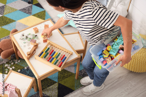 Konstfotografi Tired mother picking up scattered toys in messy children's room, top view