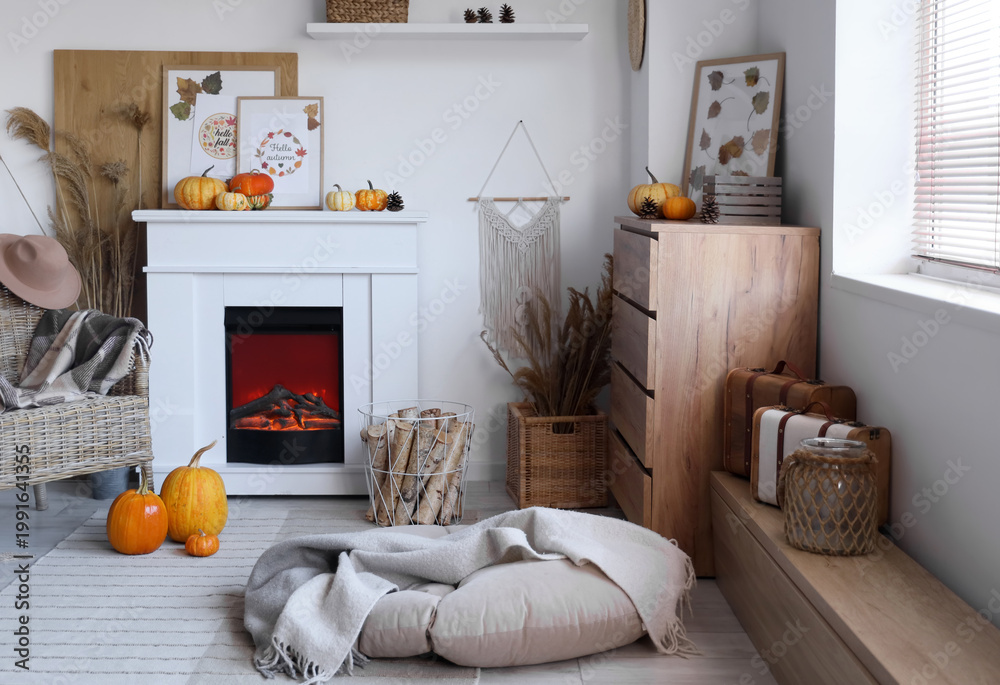 Obraz premium Interior of stylish living room with fireplace, armchair and pumpkins. Autumn concept