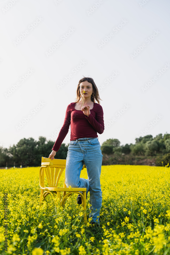 Fototapeta premium Young woman enjoying spring field with yellow flowers