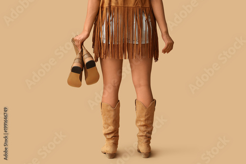 Photography Young cowgirl with boots on beige background