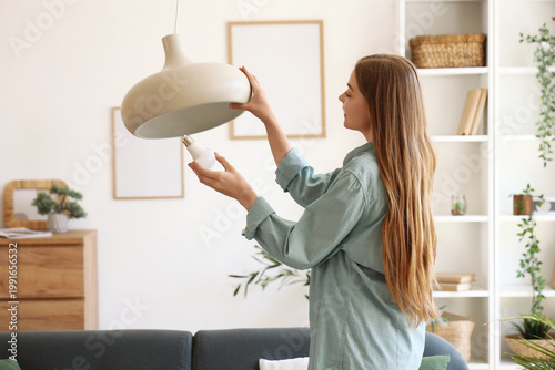 Young woman screwing light ...